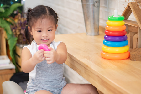 cute little girl playing educational toy, colorful ring and construction wood blockの写真素材
