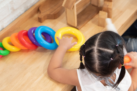 cute little girl playing educational toy, colorful ring and construction wood blockの写真素材