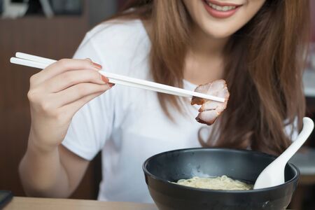woman enjoying Chinese wonton or dumpling noodle with roasted bbq pork or Char Siuの写真素材