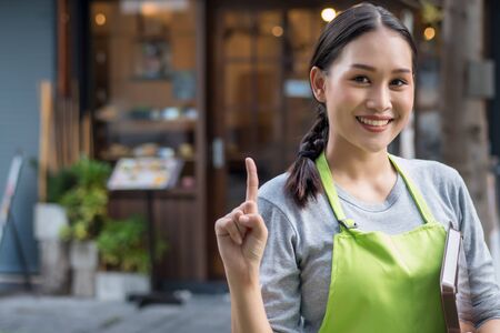 happy smiling woman entrepreneur, asian small business owner pointing up 1 fingerの写真素材