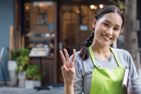 happy smiling woman entrepreneur, asian small business owner pointing up 3 fingers; three important points or counting number 3 conceptsの写真素材