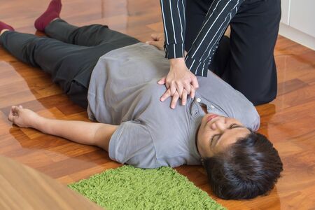young woman doing CPR first aid to middle aged or senior unconscious woman; home first aid emergency rescue conceptの写真素材