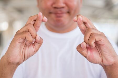 old asian man crossing finger, wishing for good luckの写真素材