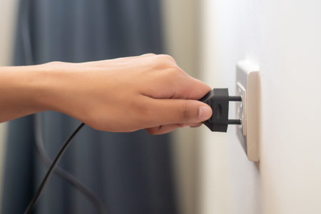 hand insetring, plugging or unplugging eclectrical wall outlet; concept of energy usage, consumption...