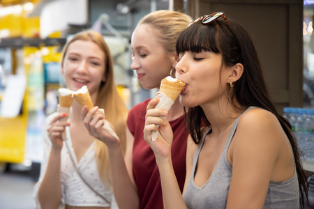 young caucasian and Latin American women eating coconut ice cream; concept of traveler or girl...