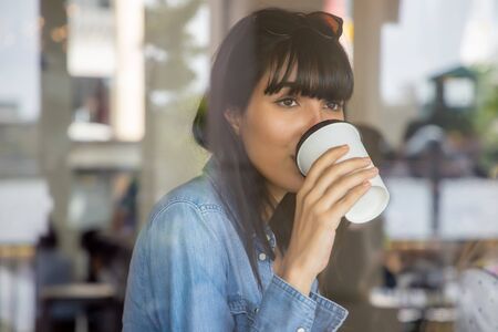 happy hispanic woman, south american latin woman drinking coffee; concept of urban lifestyle in coffee shopの写真素材