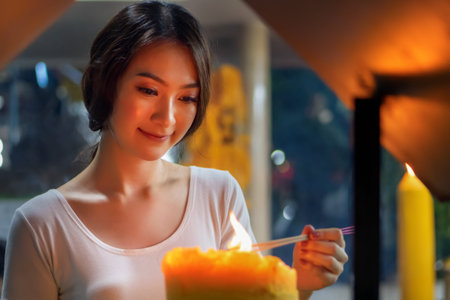 Religious Asian buddhist woman pray and light up joss stick incense. Female buddhist disciple...