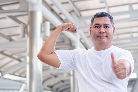strong and healthy old senior man portrait giving thumb up gesture; strong happy healthy asian senior man in city environment; senior old man model for senior citizen, pensioner, retired man conceptの写真素材