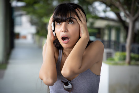 Unhappy, sad latin woman talking on smartphone; Latin American woman chatting via smartphone with...