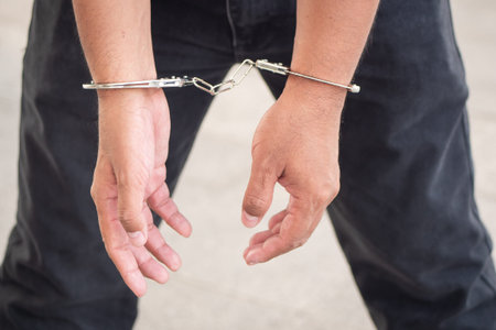 arrested man criminal gets locked up by handcuff; crime scene investigation with man getting...