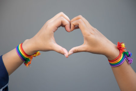 hand of LGBT women holding together, forming heart shape with rainbow ribbon symbol; concept of LGBT pride, LGBTQ people, lgbt rights campaign, same sex marriageの写真素材