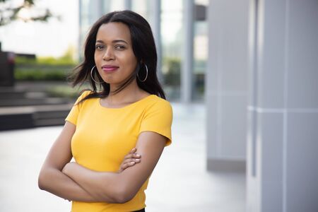 Confident African woman crossing arm; portrait of happy confident black African woman crossing her arm in urban environmentの写真素材