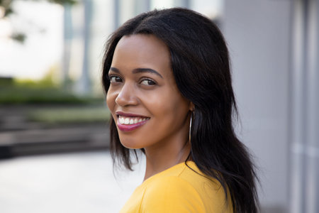 African woman looking; portrait of happy confident black African woman looking back over shoulder to youの写真素材