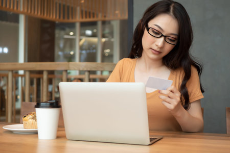woman shopping online with credit card, woman browsing the internet with laptop computer; concept of...
