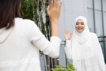 Muslim woman or Muslimah greeting her friend; Concept of friendly Islamic woman, religion of peace, Ramadan, Salam, As-salamu alaykum, Peace be upon you; Asian Muslim young adult woman modelの写真素材