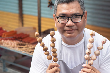 street hawker man working with his delicious meatball skewer street food; concept of asian street...