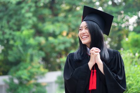 happy smiling college student graduating looking up; concept of successful education, happy commencement day, woman education opportunity, graduation, education vision, overseas study scholarshipsの写真素材