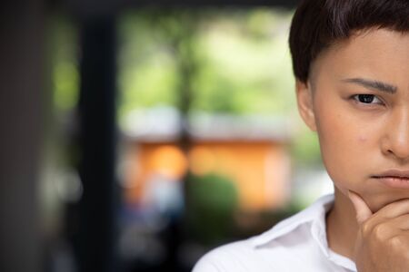 unhappy worried woman with acne on her cheek face; concept of facial skin care, acne treatment, pimple, zit inflammationの写真素材