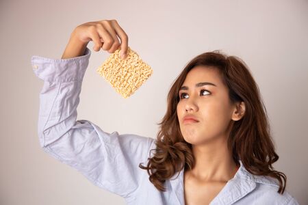 unhappy, sad girl looking up, having instant noodle; concept of cheap budget fast food for jobless girl, unemployed people, month end, no money, no incomeの写真素材