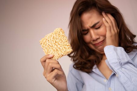 unhappy, sad girl having instant noodle, concept of cheap budget fast food for jobless girl, unemployed people, month end, no money, no incomeの写真素材