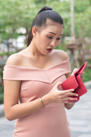 poor woman without money, empty wallet; portrait of poor woman with empty wallet, poor people, poverty, bankruptcy, economic recession, depression, unemployment, concept; asian young adult woman modelの写真素材