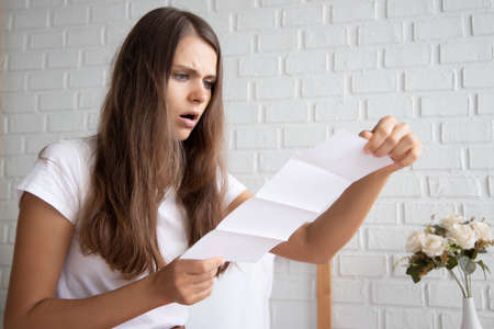 frustrated, shocked, stressed women with expensive bill, debt invoice, eviction notice; concept of high cost of living, expensive bill, getting busted, economic recession, no job no moneyの写真素材