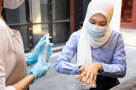 Muslim woman suggesting to wear face mask in outdoor public; concept of new normal lifestyle, social...