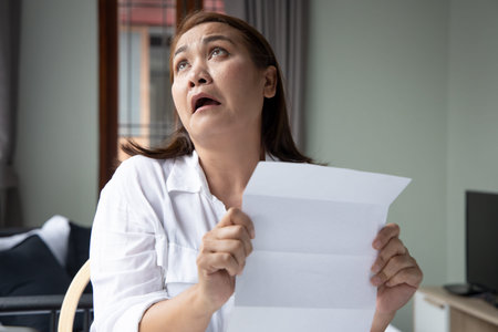 exhausted middle aged woman getting fed up with expensive bill, debt invoice, eviction notice;...