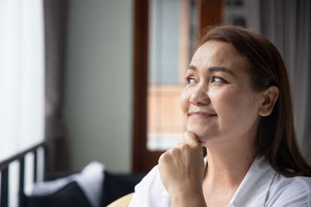 happy middle aged woman thinking, looking upの写真素材