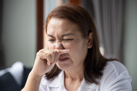 sick asian middle aged woman getting a cold or flu with runny nose, coronavirus infection or...