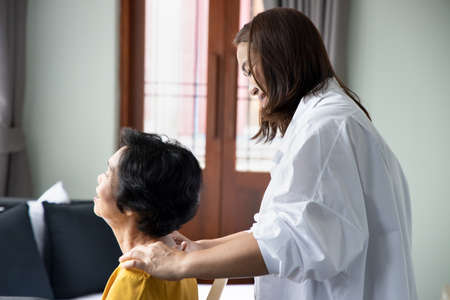 Asian caregiver massaging retired senior woman, concept of retirement, old age home, senior home, pensioner service, caretaker businessの写真素材