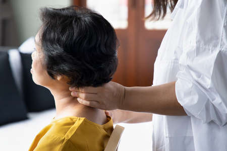 Asian caregiver massaging retired senior woman, concept of retirement, old age home, senior home, pensioner service, caretaker businessの写真素材