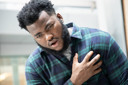 sick african man with heart attack or chest pain; portrait of african man suffering from heart...