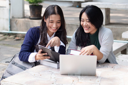 Happy asian woman college student studying in university campus with her classmate or tutor, concept of back to school, video call online learning class, teleeducation, online education lifestyleの写真素材