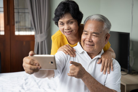 Happy old asian senior couple using smartphone for video call, selfie, taking photoの写真素材