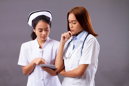 Professional female doctor and nurse, medical team, health care worker working together with computer tablet, telemedicine conceptの写真素材
