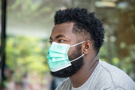 Symptometic black african man wearing hygienic face mask and having breathing difficultiesの写真素材