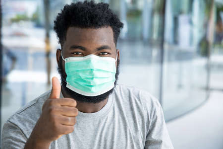 Symptometic black african man wearing hygienic face mask and having breathing difficultiesの写真素材