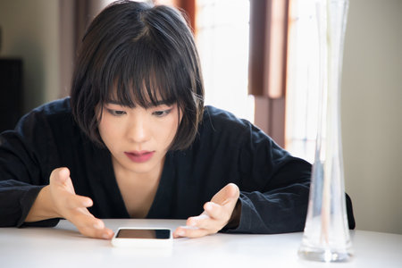 Angry upset asian woman with smartphone, problem concept of online shopping, distant togetherness, online deal, smartphone app transaction, tele medicine, new normal video call, social distancingの写真素材