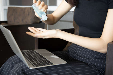 asian woman working with computer with new normal lifestyle, using alcohol gel hand sanitizerの写真素材