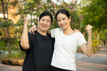 Healthy and strong senior mother staying in the park with asian young adult daughter, concept of senior health care, healthy lifestyle, wellness, family togetherness, mother and daughter, mother dayの写真素材