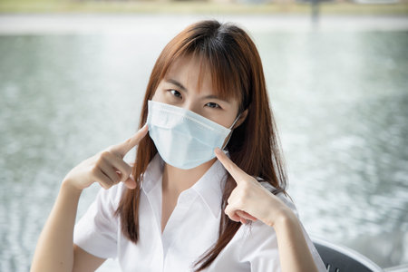Sick asian woman wearing mask sneezing to her elbow, prevention measure against the spreading of...