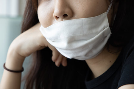 young Asian woman properly wearing face mask in working office, concept of taking precaution measure, social distancing, new normal lifestyle while waiting for coronavirus cure, COVID-19 vaccineの写真素材