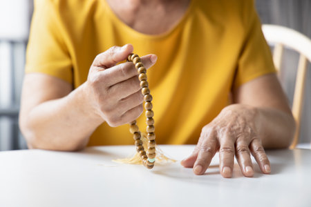 Asian senior woman praying and meditating with religious rosary, concept of social distancing religious service at home, praying at homeの写真素材