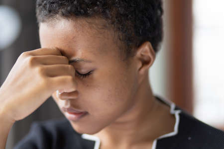 sick African woman having fever or headache, concept of virus infection, coronavirus COVID-19 flu, vaccine adverse effect, vertigo, dizziness, depression, depressed woman, health care medical conceptの写真素材