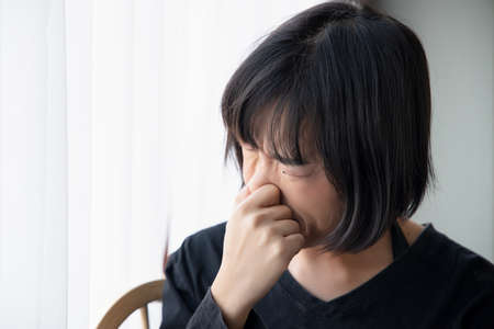 asian woman covering her nose for bad smell, concept of stink thing, bad breath, unpleasant smell, rotten food, odor, body bad smell, air pollution, polluted airの写真素材