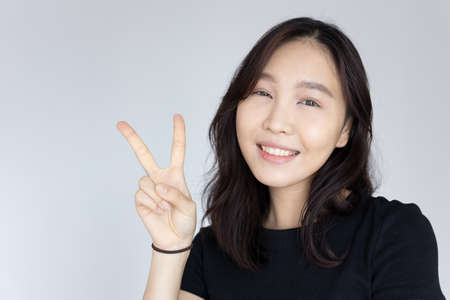asian woman pointing, counting five finger; portrait of positive happy smiling asian woman pointing up 5 fingers for number five or 5 points conceptの写真素材