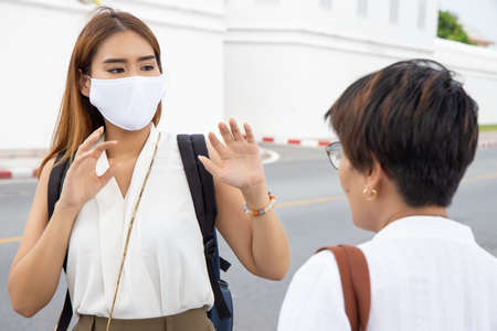 Fearful vaccinated woman wearing mask having a hard time with unvaccinated anti-vaxxer people without face maskの写真素材