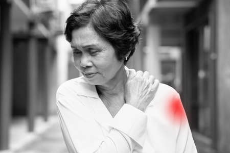 Vaccinated asian senior woman suffering from vaccine side effect, post shot adverse effect of upper arm muscle pain with redness and swelling at vax injection siteの写真素材