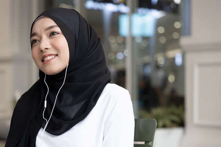 happy muslim woman enjoying smartphone music streaming download serviceの写真素材